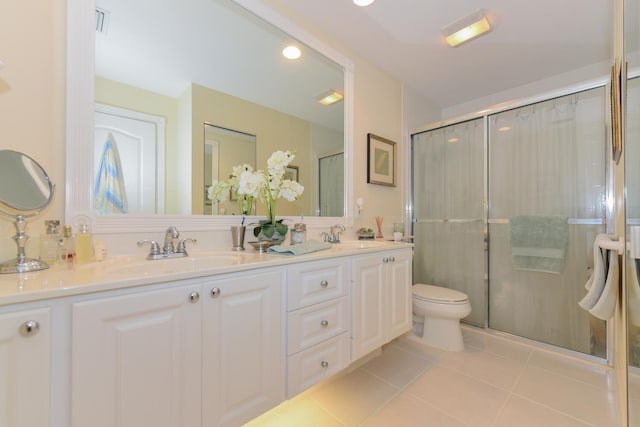 bathroom with tile patterned flooring, vanity, a shower with door, and toilet