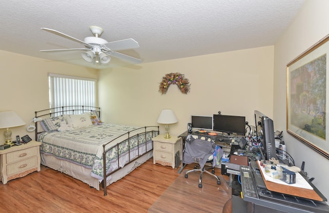 bedroom featuring ceiling fan, wood-type flooring, and a textured ceiling