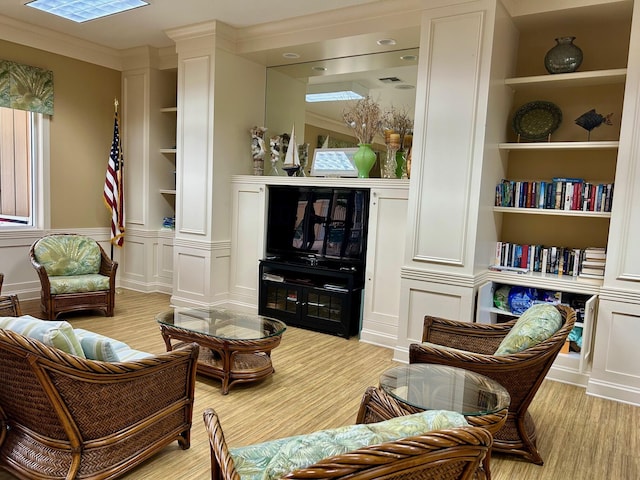 sitting room with ornamental molding, light hardwood / wood-style flooring, and built in features