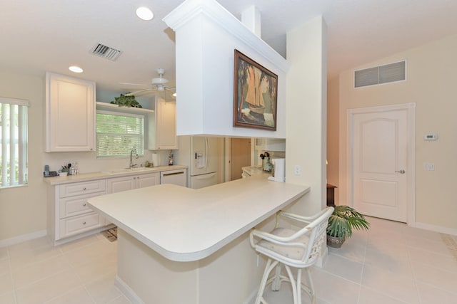 kitchen with white cabinetry, a breakfast bar, kitchen peninsula, and light tile patterned floors