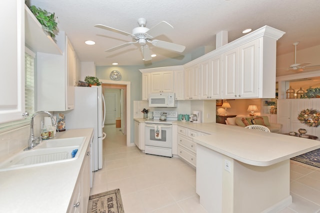 kitchen featuring sink, white appliances, white cabinets, a kitchen bar, and kitchen peninsula