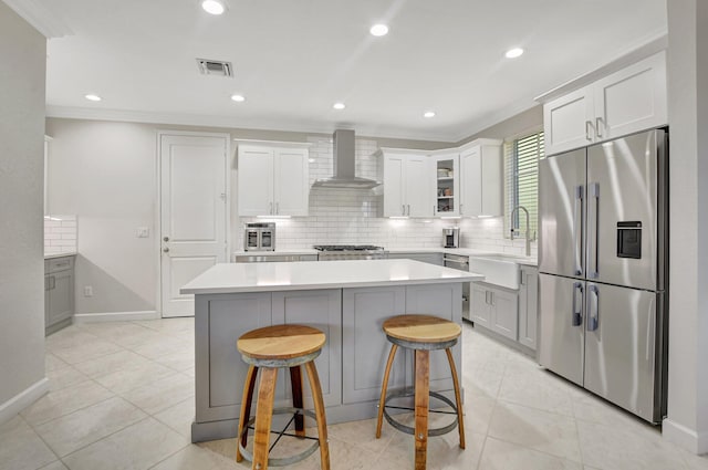 kitchen featuring a center island, stainless steel refrigerator with ice dispenser, visible vents, a sink, and wall chimney exhaust hood