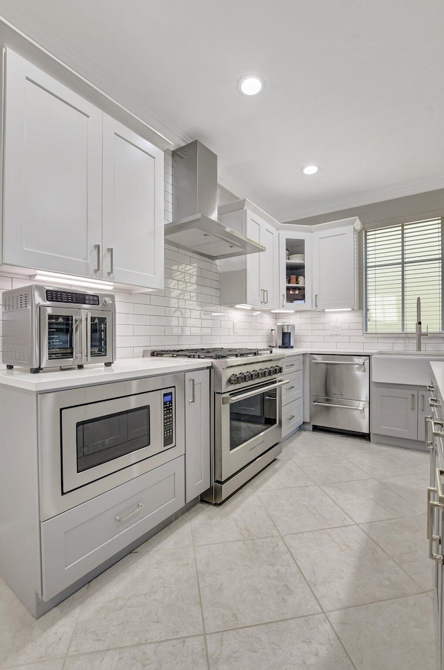 kitchen with stainless steel appliances, a sink, light countertops, ventilation hood, and backsplash