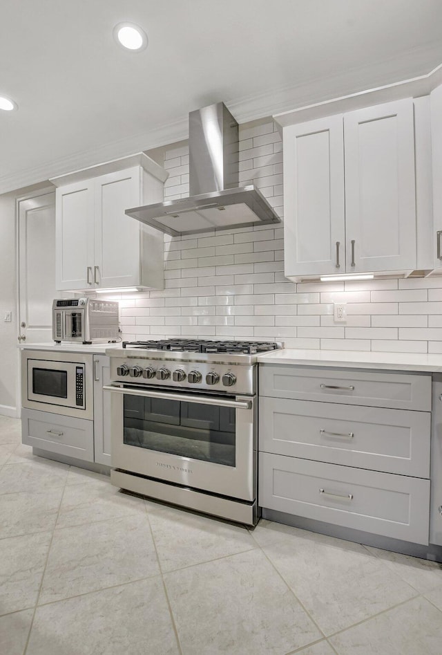 kitchen with wall chimney exhaust hood, ornamental molding, backsplash, and stainless steel appliances