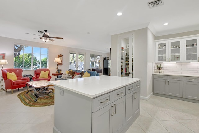 kitchen featuring open floor plan, visible vents, crown molding, and decorative backsplash