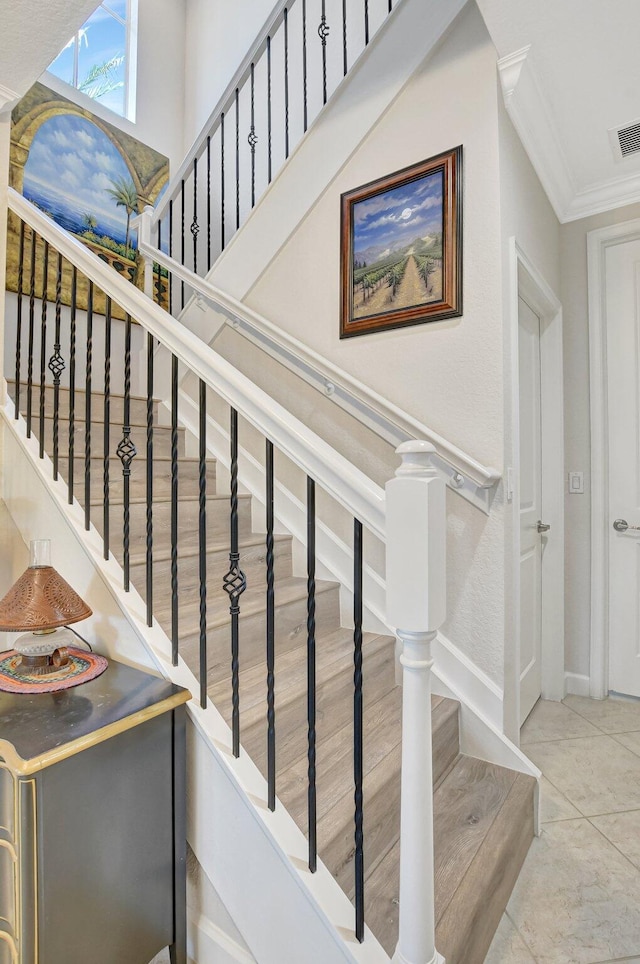 stairway featuring baseboards, visible vents, and crown molding