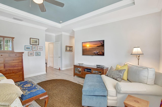 living room with wood finished floors, a raised ceiling, visible vents, and crown molding