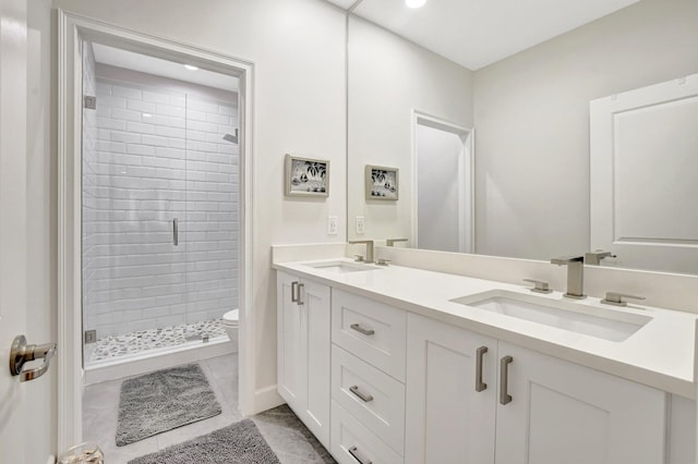 bathroom with double vanity, a stall shower, a sink, and toilet