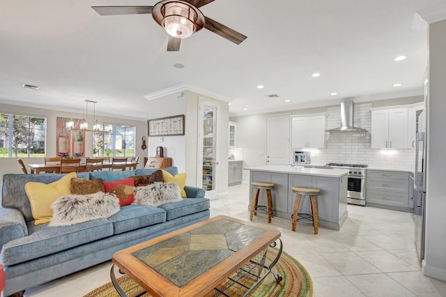 living room with light tile patterned floors, visible vents, ceiling fan with notable chandelier, crown molding, and recessed lighting