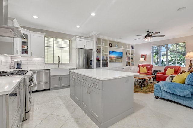 kitchen featuring light countertops, appliances with stainless steel finishes, open floor plan, a sink, and exhaust hood