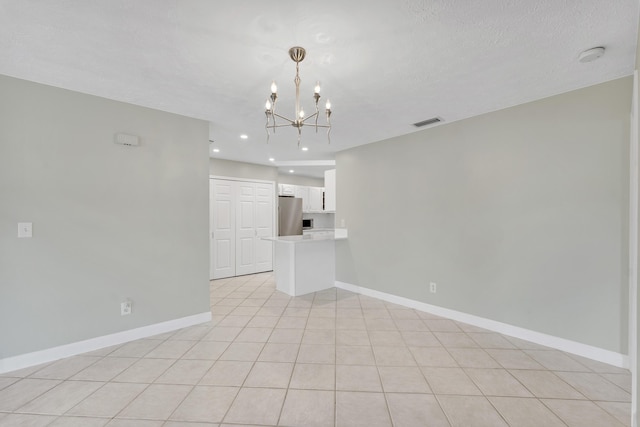 unfurnished living room featuring a textured ceiling, visible vents, baseboards, recessed lighting, and an inviting chandelier