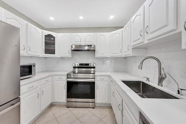 kitchen with a sink, under cabinet range hood, light tile patterned floors, stainless steel appliances, and white cabinets