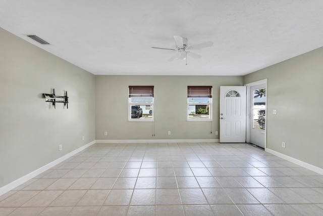 interior space featuring light tile patterned floors, visible vents, baseboards, and ceiling fan
