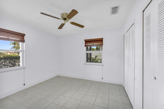 unfurnished bedroom featuring baseboards, visible vents, light tile patterned floors, and a ceiling fan