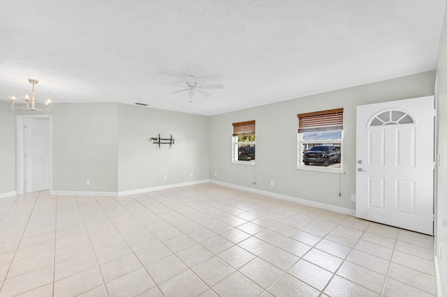 spare room with baseboards, light tile patterned floors, a textured ceiling, and ceiling fan with notable chandelier