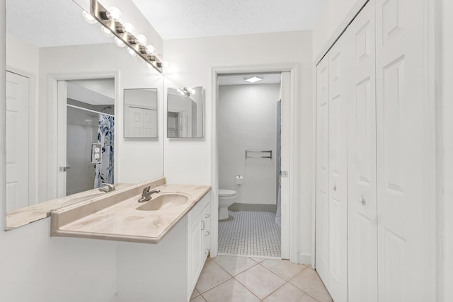 bathroom with a closet, toilet, tile patterned flooring, and a textured ceiling