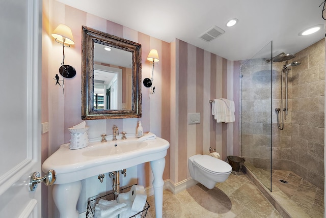 bathroom with a tile shower and toilet