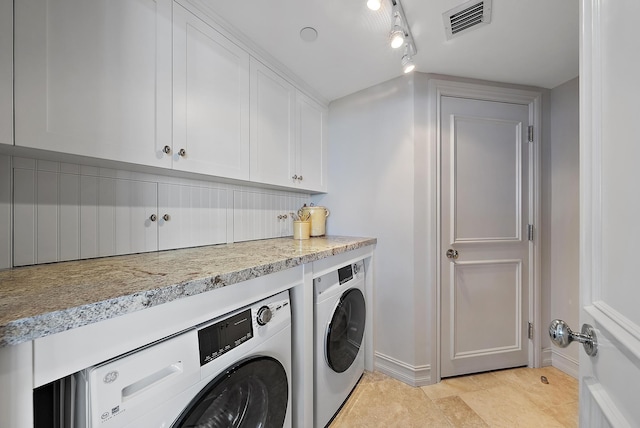 washroom featuring cabinets, rail lighting, washer and clothes dryer, and light tile patterned floors