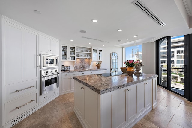 kitchen with a center island, dark stone countertops, appliances with stainless steel finishes, decorative backsplash, and white cabinets