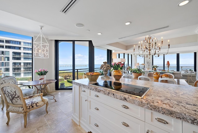 kitchen with a water view, white cabinetry, black electric stovetop, and a chandelier