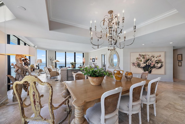 dining room featuring a raised ceiling, ornamental molding, an inviting chandelier, and a wall of windows