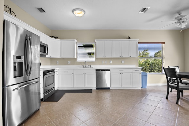 kitchen with appliances with stainless steel finishes, light countertops, ceiling fan, and a sink