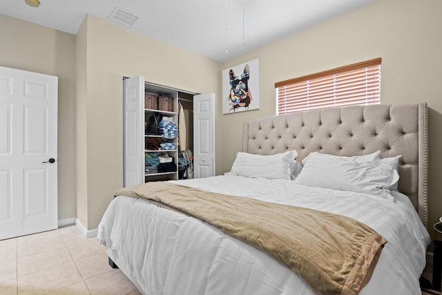 bedroom featuring light tile patterned floors, baseboards, visible vents, and a closet