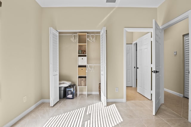 unfurnished bedroom with light tile patterned floors, visible vents, a closet, and baseboards