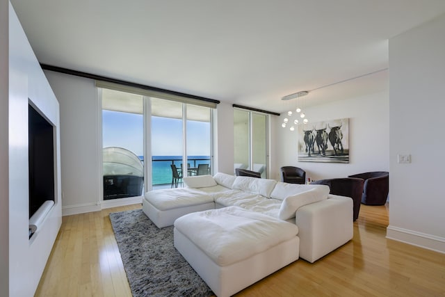 living room with a wall of windows, light hardwood / wood-style floors, and a water view