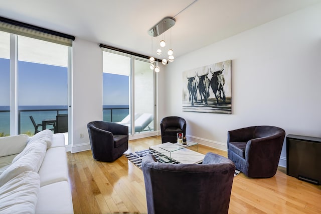 living room with hardwood / wood-style floors, a notable chandelier, expansive windows, and a water view