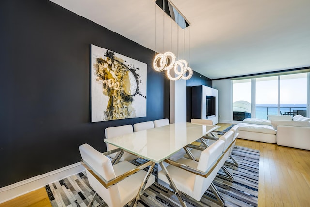 dining space with wood-type flooring, floor to ceiling windows, and a notable chandelier