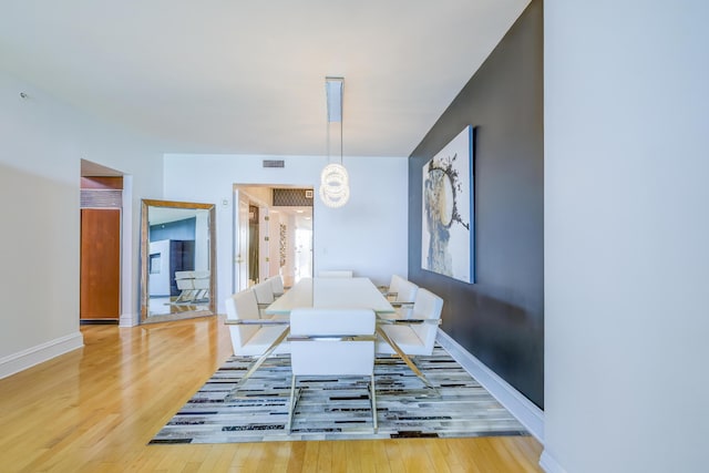 dining area with hardwood / wood-style flooring and a notable chandelier