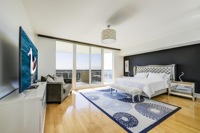 bedroom with floor to ceiling windows, wood-type flooring, and access to exterior