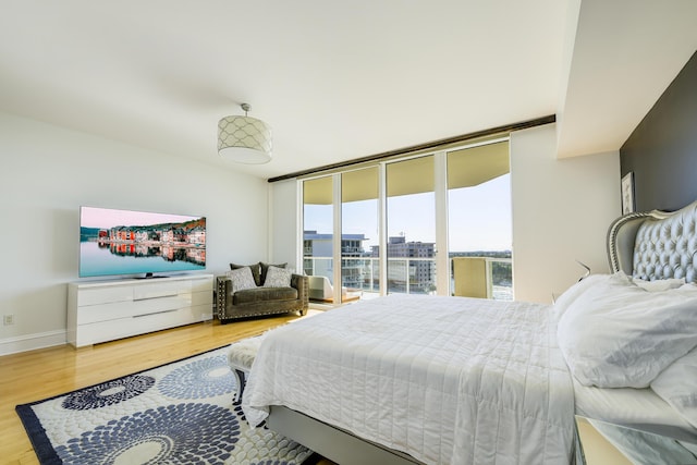 bedroom with a wall of windows, hardwood / wood-style floors, and access to outside