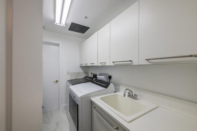 clothes washing area featuring cabinets, sink, and independent washer and dryer