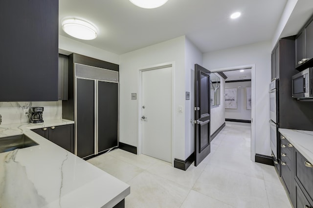 kitchen with sink, light tile patterned floors, light stone countertops, and stainless steel appliances