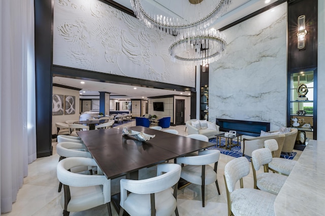 dining space with a premium fireplace, a towering ceiling, and a chandelier