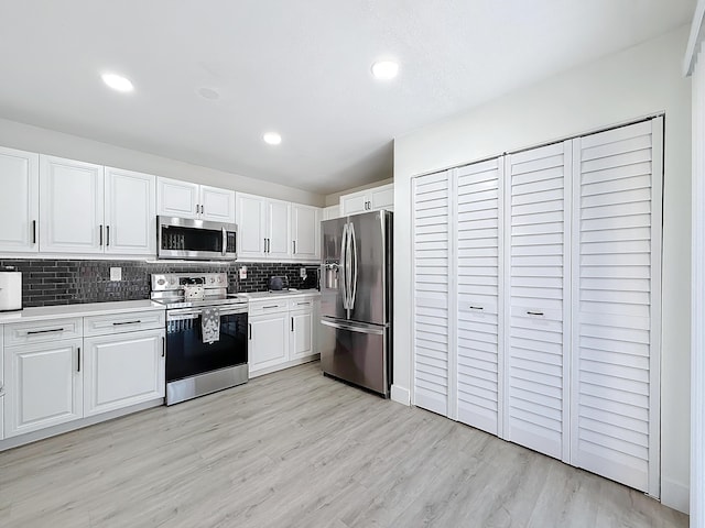 kitchen with white cabinetry, stainless steel appliances, tasteful backsplash, and light hardwood / wood-style flooring