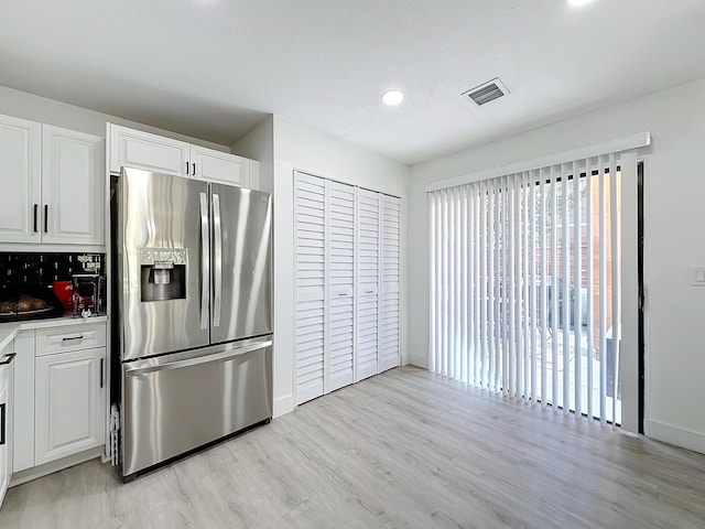 kitchen featuring backsplash, stainless steel fridge with ice dispenser, light hardwood / wood-style flooring, and white cabinets