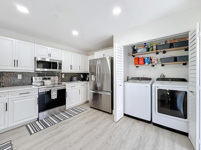 kitchen with appliances with stainless steel finishes, white cabinetry, separate washer and dryer, decorative backsplash, and light wood-type flooring