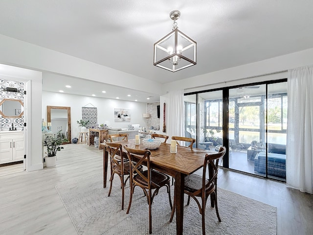 dining area with sink, a chandelier, and light wood-type flooring