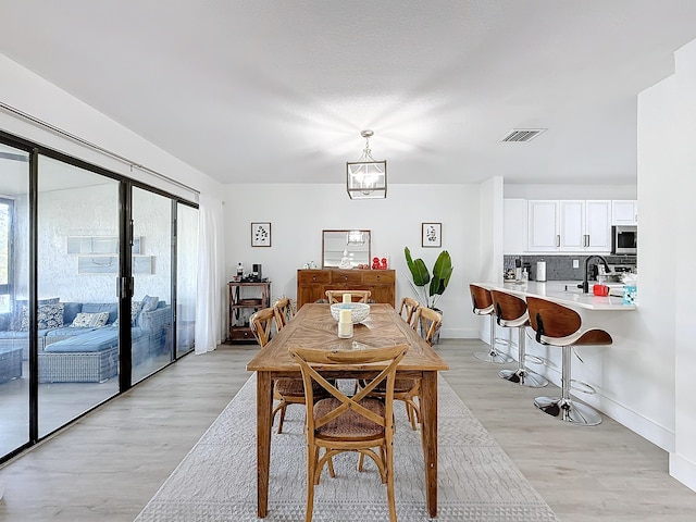 dining room featuring a notable chandelier, sink, and light wood-type flooring