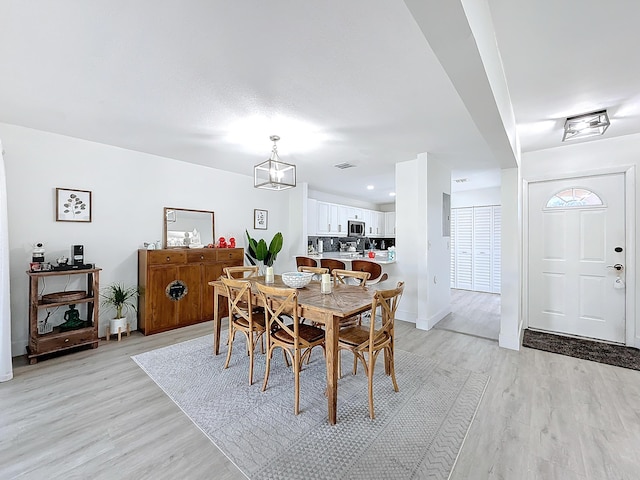 dining space featuring a notable chandelier and light wood-type flooring