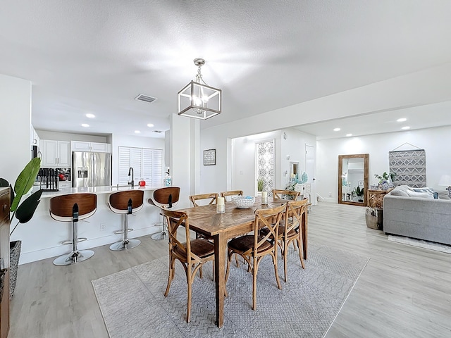 dining area featuring an inviting chandelier, a textured ceiling, and light wood-type flooring