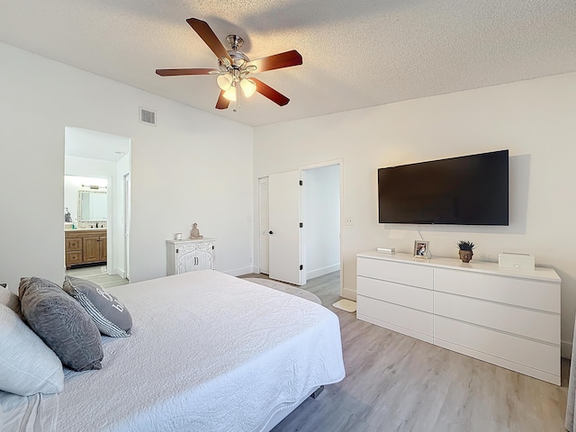 bedroom featuring ensuite bath, lofted ceiling, ceiling fan, light hardwood / wood-style floors, and a textured ceiling