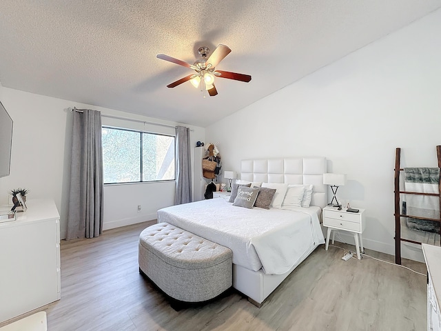 bedroom featuring ceiling fan, lofted ceiling, a textured ceiling, and light wood-type flooring