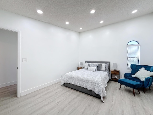 bedroom with a textured ceiling and light hardwood / wood-style flooring