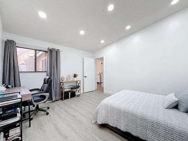 bedroom with a textured ceiling and light hardwood / wood-style floors