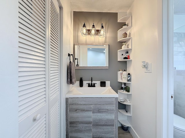 bathroom with vanity, toilet, and a textured ceiling