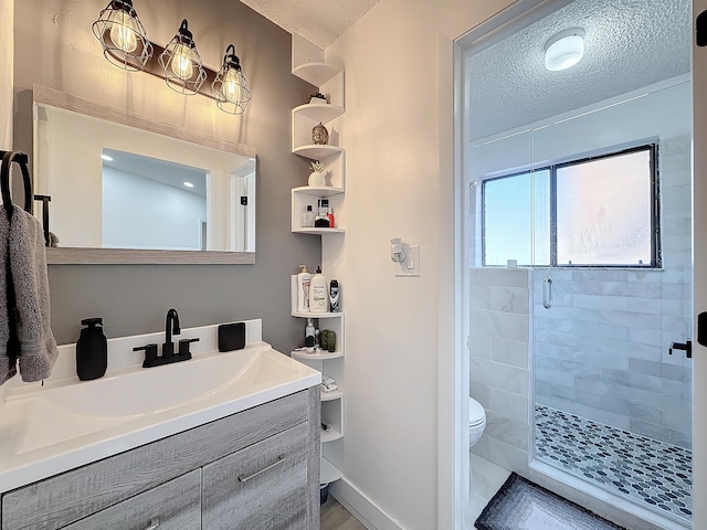 bathroom featuring vanity, toilet, an enclosed shower, and a textured ceiling